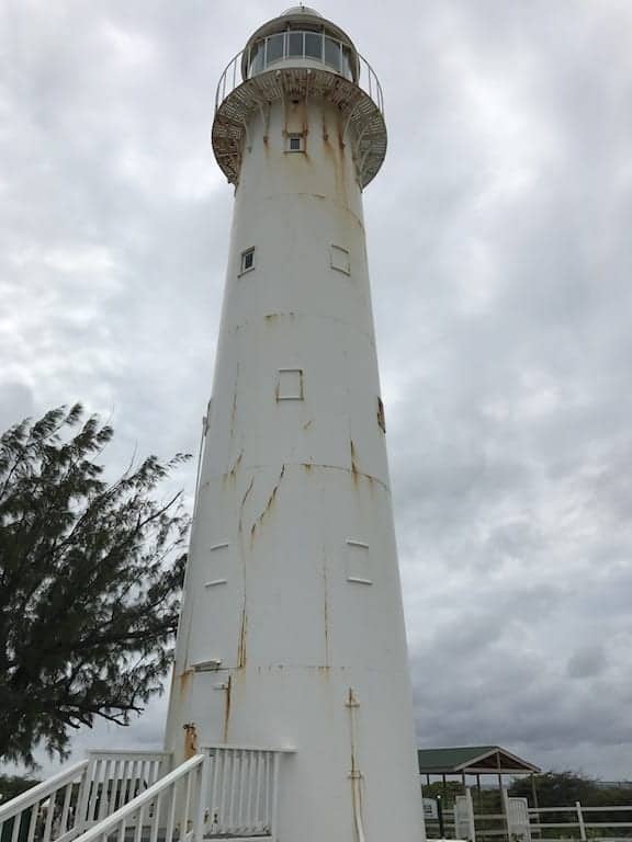 A lighthouse stands tall and solitary, its white structure contrasting against a clear blue sky.