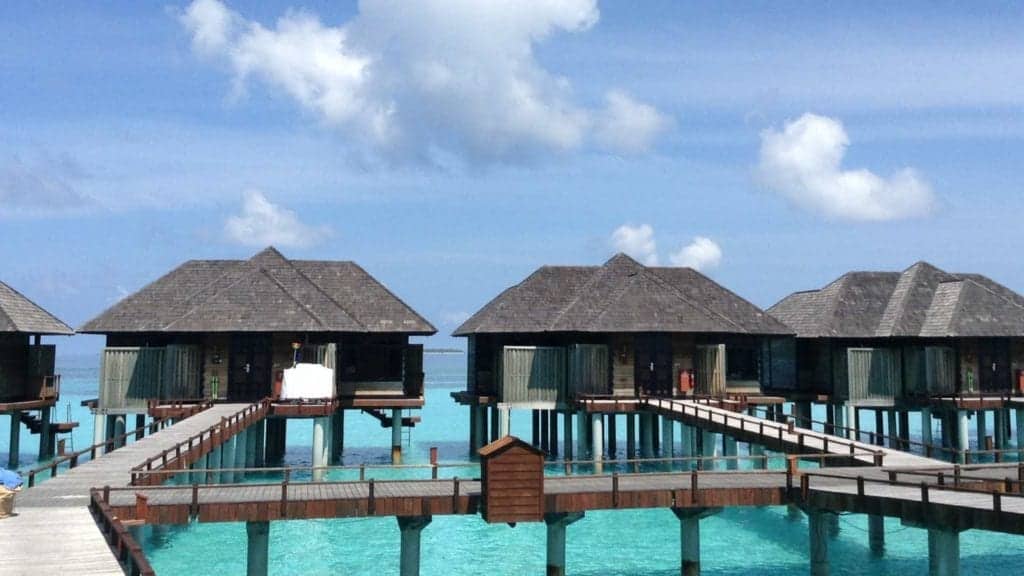 A row of resort houses sits on stilts above the crystal clear waters of the ocean, in Jamaica.