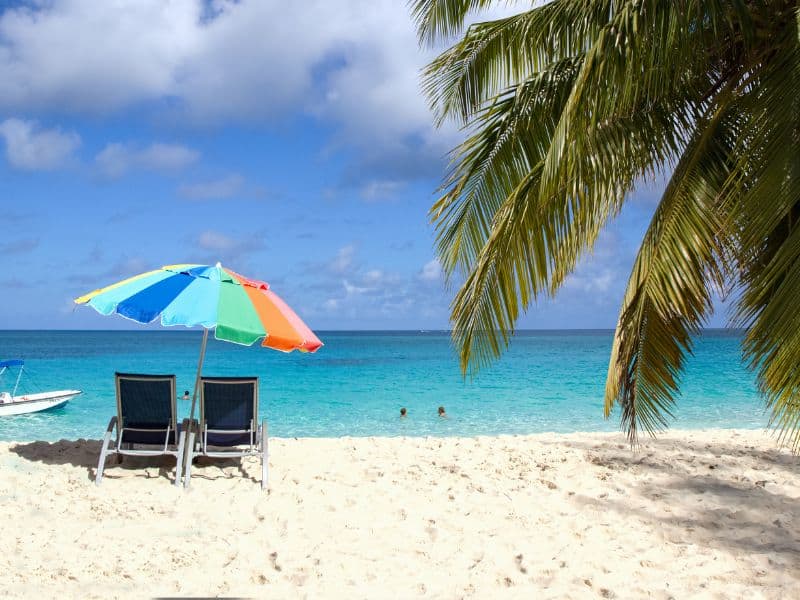 10 Unmissable Experiences in Nassau That Will Make Your Bahamas Trip Unforgettable! 12 British Colonial's Serenity Beach in the Bahamas, featuring a beach umbrella, chair, and coconut tree in the picturesque view.