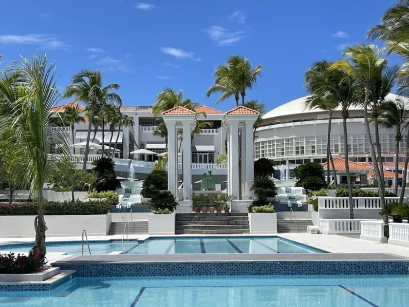  El Conquistador Resort, showcases its pool area adorned with palm trees and the resort's distinctive white-colored building, creating a picturesque and luxurious tropical setting.