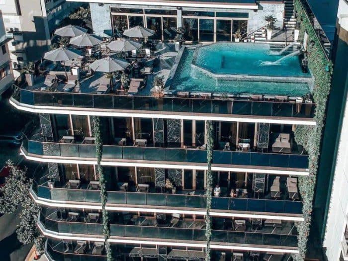  O:LV Fifty Five Hotel, focusing on its rooftop pool , the pool's calm waters contrast with the hotel's modern architecture, emphasizing its luxurious ambiance. 