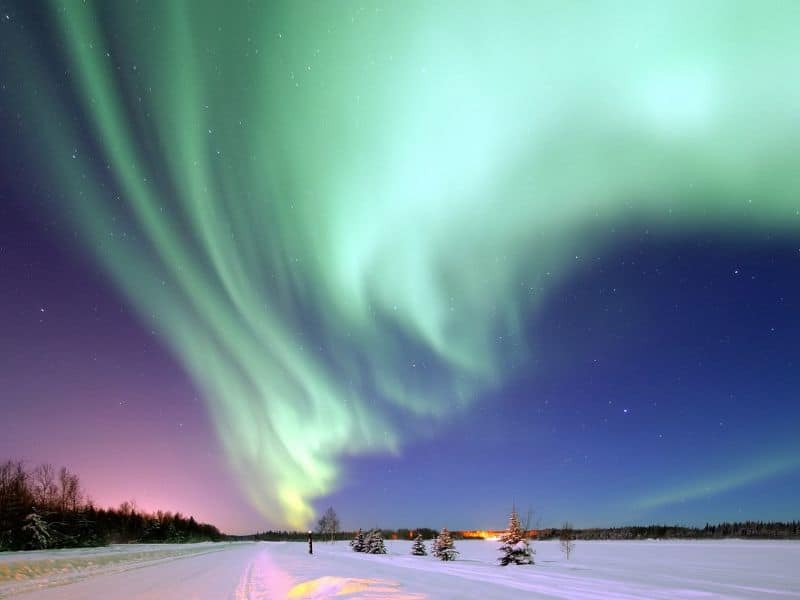 A stunning display of the Northern Lights with vibrant green and pink hues dancing across the night sky.