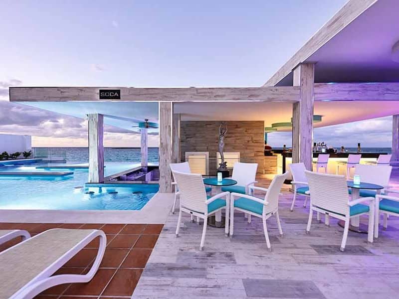 luxurious RIU Palace in Nassau, prominently featuring its magnificent pool areas against the backdrop of the serene ocean. 