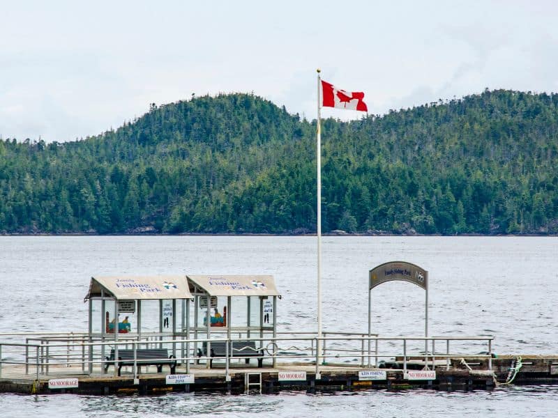 Is Vancouver Island Worth Visiting? 15 Reasons to visit! 10 Canadian Flag over the water with mountains in background