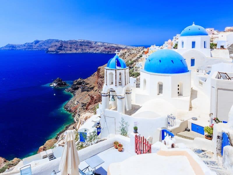 White buildings with blue domes above blue water