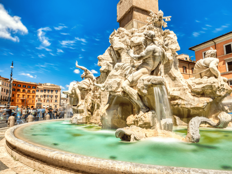 30 Famous Rome Italy Landmarks That You Must See 13 The Fontana dei Quattro Fiumi is a stunningly majestic sight, with its four rivers flowing majestically from the center. And tourists admiring its beauty and grandeur.