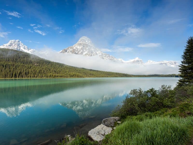 Hector Lake with snow capped mountains and cloud cover