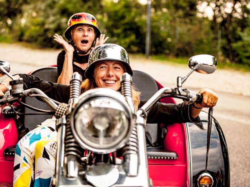 Two joyous girls gleefully riding a trike through the streets of Cartagena, Spain, their laughter echoing the vibrant energy of the city.