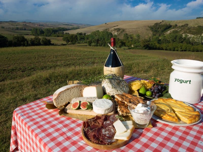 10 Best Livorno Shore Excursions 15 A delightful Tuscany wine-tasting experience featuring a table adorned with an assortment of delicious treats. Glasses of fine Tuscany wine accompany a selection of cheese, yogurt, ham, breads, and fresh grapes, creating a mouthwatering spread that perfectly complements the enchanting tuscany countryside.