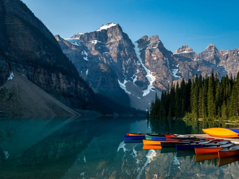 Vibrantly colored canoes parked on the tranquil waters of Lake Louise, creating a striking contrast against the backdrop of the majestic Rocky Mountains.