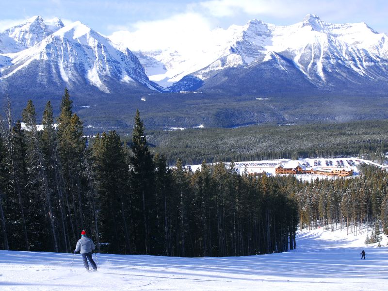 When is the Best Time to Visit Banff, Canada? 14 Capture the essence of winter excitement with a man gracefully skiing down the slopes. At the same time, another tackles the mountain on a snowboard, both enjoying the thrill of the Banff winter wonderland against the stunning backdrop of the Canadian Rockies.