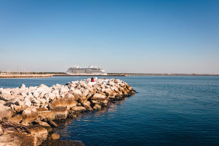 Marina di Ravenna, Emilia Romagna - Italy - August 2020: Rocks with people with cruise ship in the background