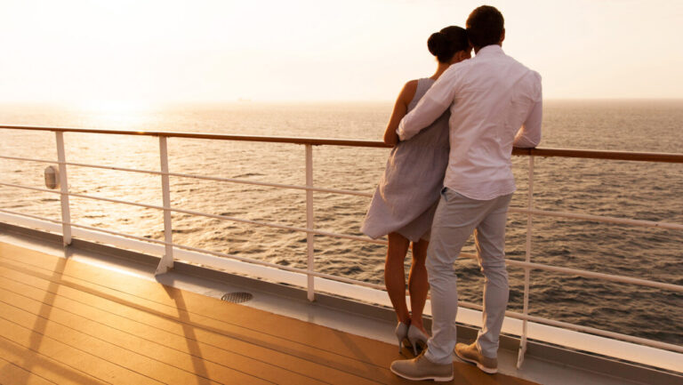 back view of young couple hugging at sunset on cruise ship