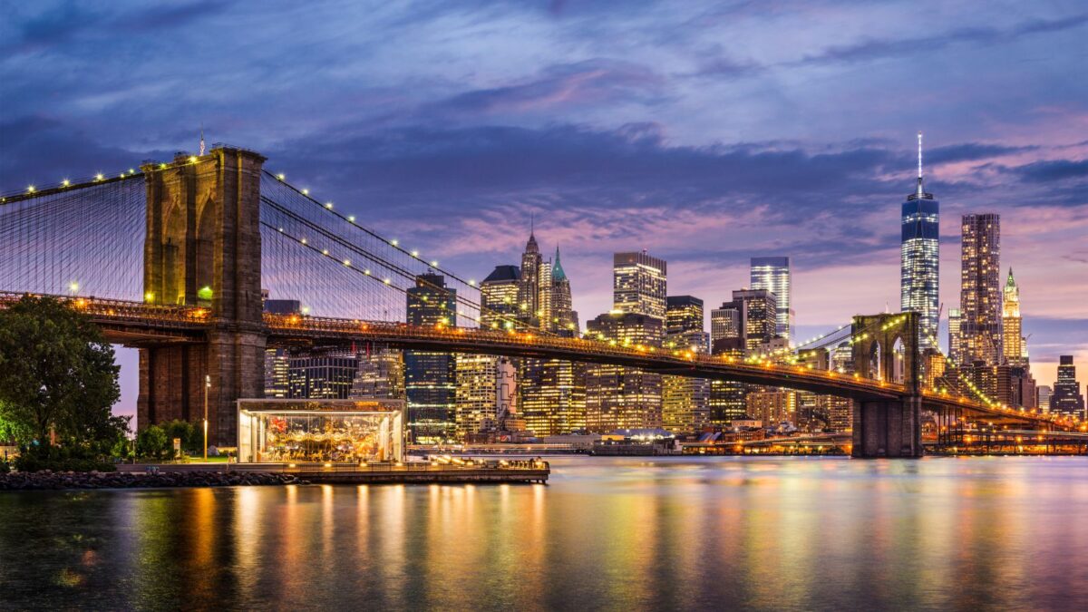 Skyline of NYC at night with brooklyn bridge in forefront
