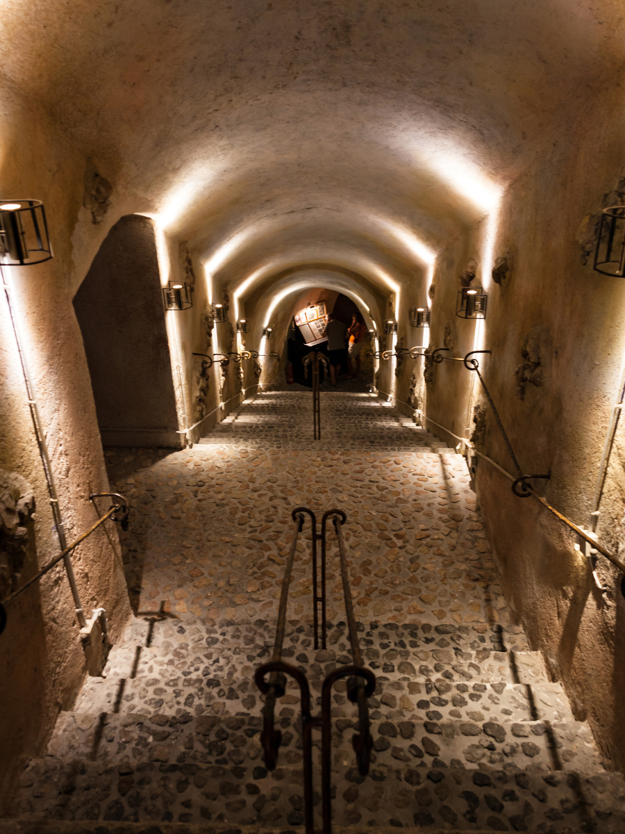 Inside Koutsoyannopoulos Winery, featuring ambient lights and a staircase leading to the underground cellar.