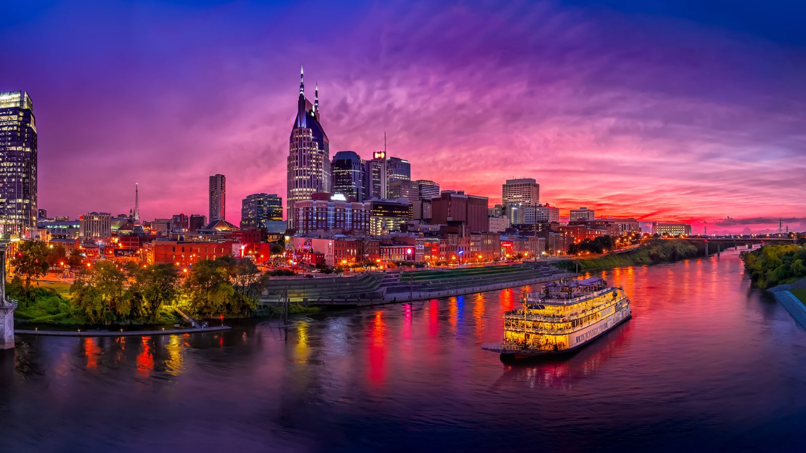10 Travel Spots Every True Swiftie Will Know 6 A breathtaking panoramic view of Nashville at sunset, with the city's lights reflecting on the river and a traditional paddle steamer cruising by.