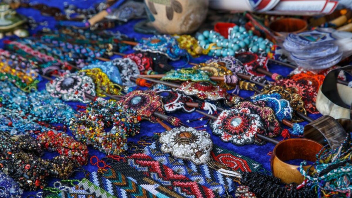 An array of colorful, handcrafted souvenirs and jewelry displayed on a blue cloth.