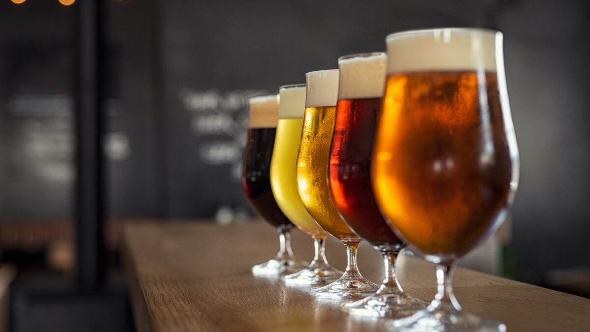 A collection of different glasses, each filled with a uniquely brewed beer, showcasing a variety of colors and foam levels.