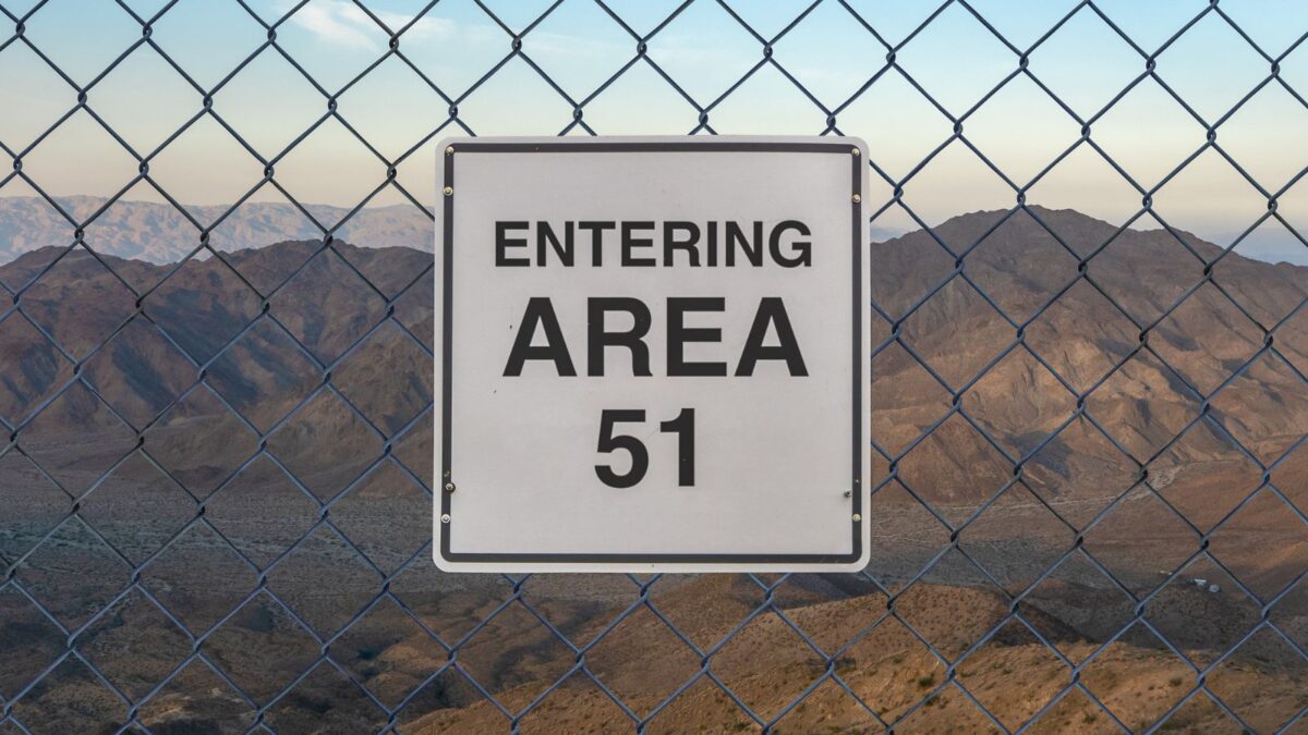 sign saying "entering area 51" on a chainlink fence