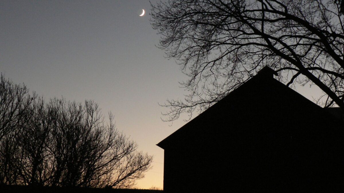 photo of a barn infront of a moon