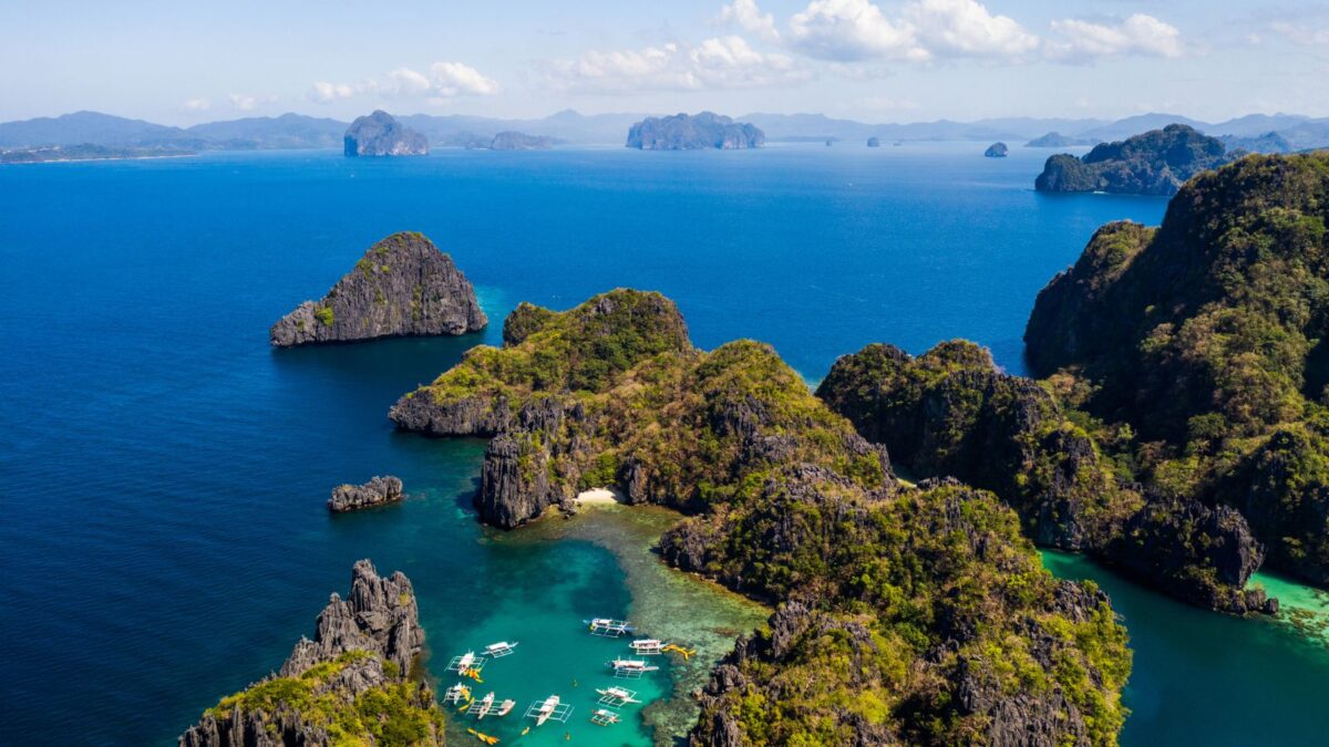 Aerial view of a tropical archipelago with boats near a lagoon in El Nido palawa, one of the most romantic places for couples in the Philippines.