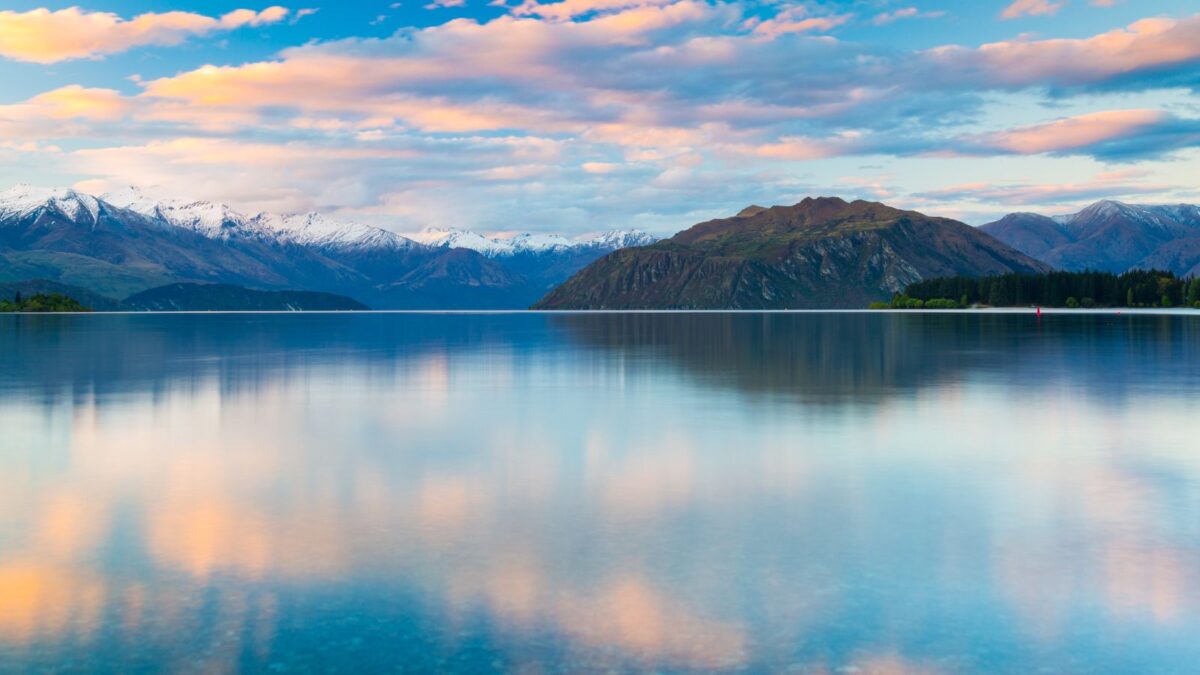 20 Breathtaking Lakes That Are True Natural Wonders! 17 The calm waters of Lake Wanaka at dusk, reflecting the pastel colors of the sky and surrounding mountains.