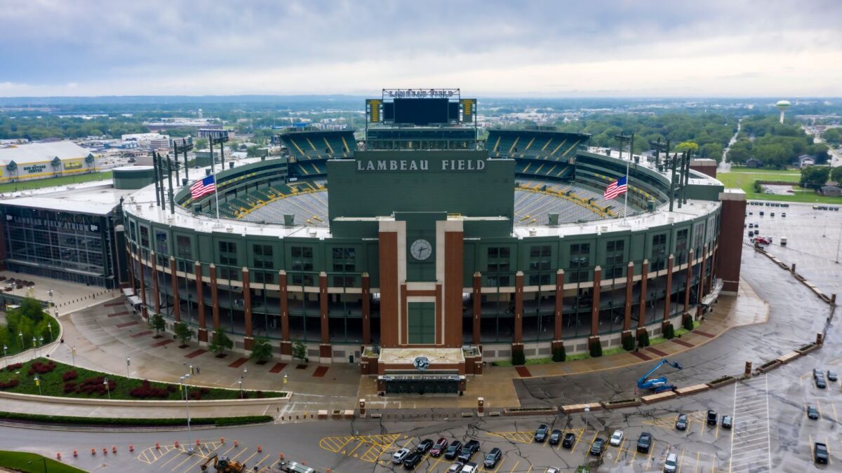 10 Iconic Football Stadiums Every Fan Should Experience 2 Lambeau Field under an overcast sky, showcasing its classic brick facade and the Green Bay Packers' branding. The stadium's grandeur is amplified by its historical aura and the vast parking lot surrounding it.