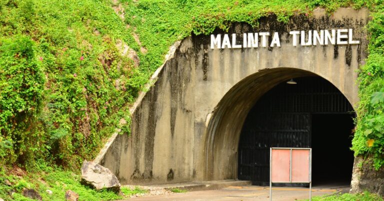 Entrance to the Malinta Tunnel with lush greenery overhead and a red door, located in the Philippines