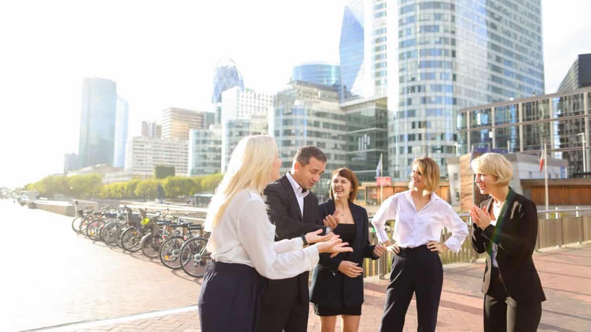 Group of businessman and women talking outside near the buildings.