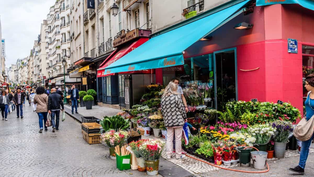 A flower shop in the corner of a street in France.