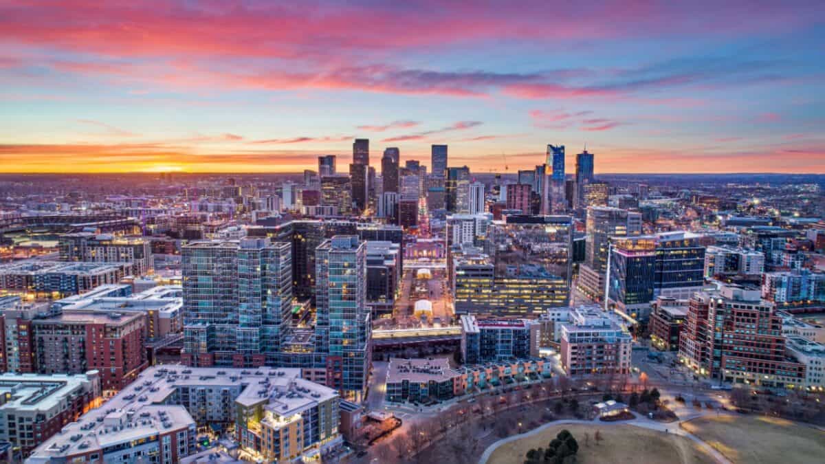 Aerial view of a city skyline at twilight with a vivid sunset painting the sky in beautiful shades of pink, blue, and orange.
