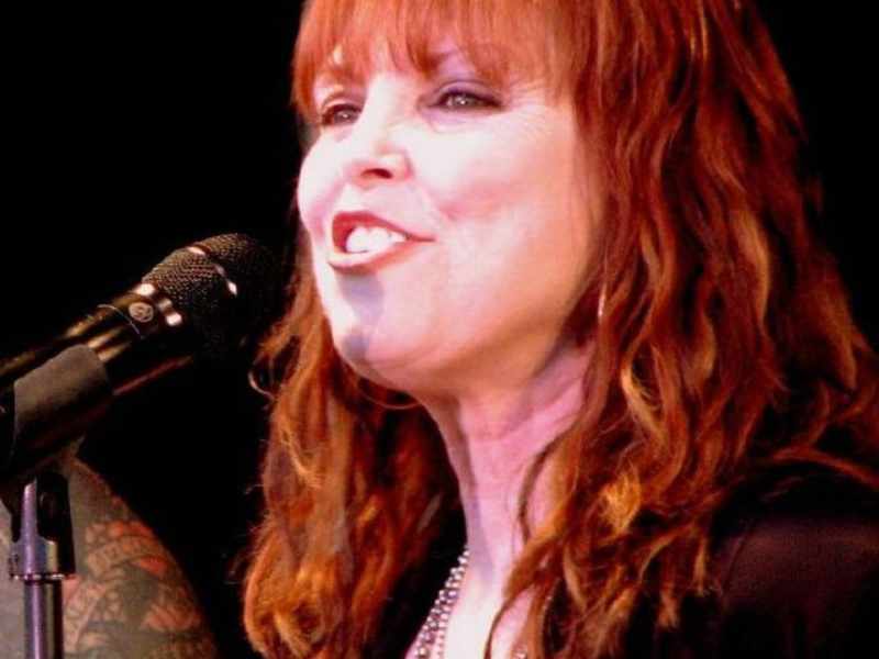 The 15 Best '80s Breakup Songs 10 A female singer with long red hair performing at a microphone, exuding passion and energy with the best 80s breakup songs.