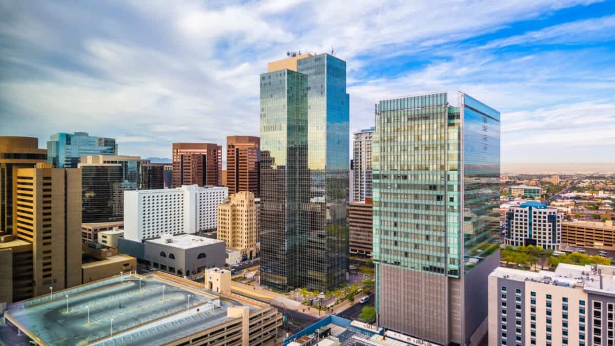 Modern city skyline with a mix of reflective glass skyscrapers and traditional buildings under a partly cloudy sky.