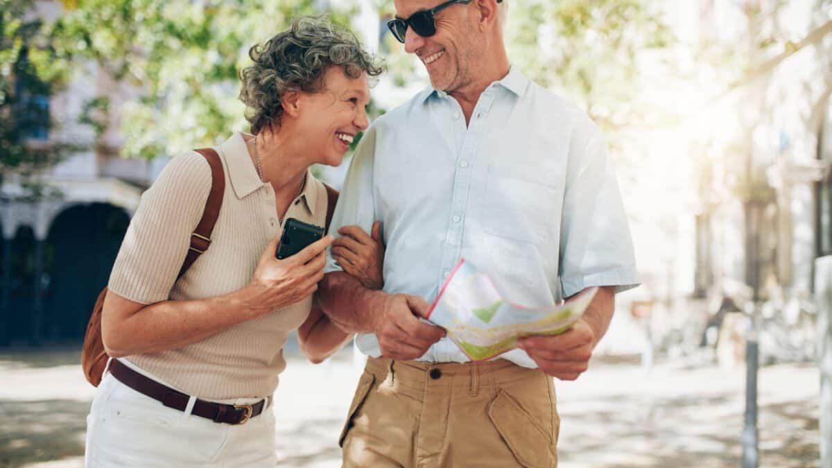 Joyful senior couple sharing a laugh while looking at a map on a sunny day in the city.