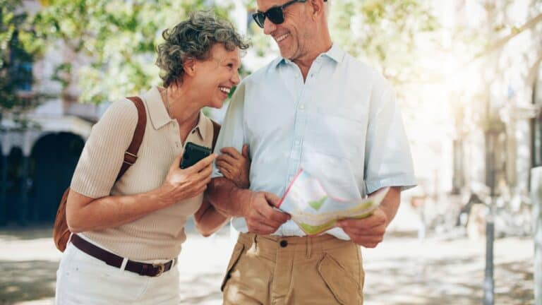 Joyful senior couple sharing a laugh while looking at a map on a sunny day in the city.