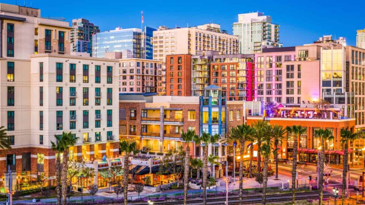 Twilight cityscape: a vibrant urban scene with modern buildings, glowing streetlights, and lush palm trees lining the bustling streets at dusk.