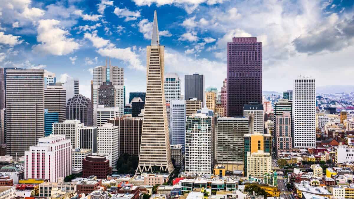 A vibrant panoramic view of a bustling city skyline dotted with skyscrapers under a partly cloudy sky.