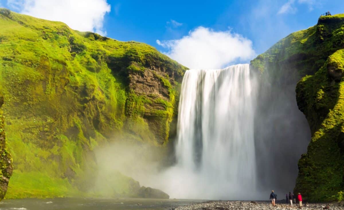 Skógafoss Waterfall in Iceland, a tall waterfalls in the middle of the mountains under a clear blue sky.
