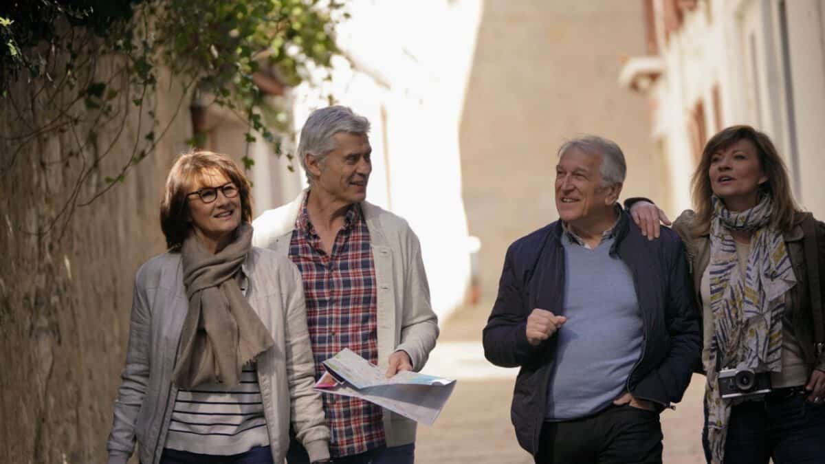 Four mature adults enjoying a leisurely stroll down a quaint alleyway, with one of them holding a map, suggesting they are tourists exploring a new city together.