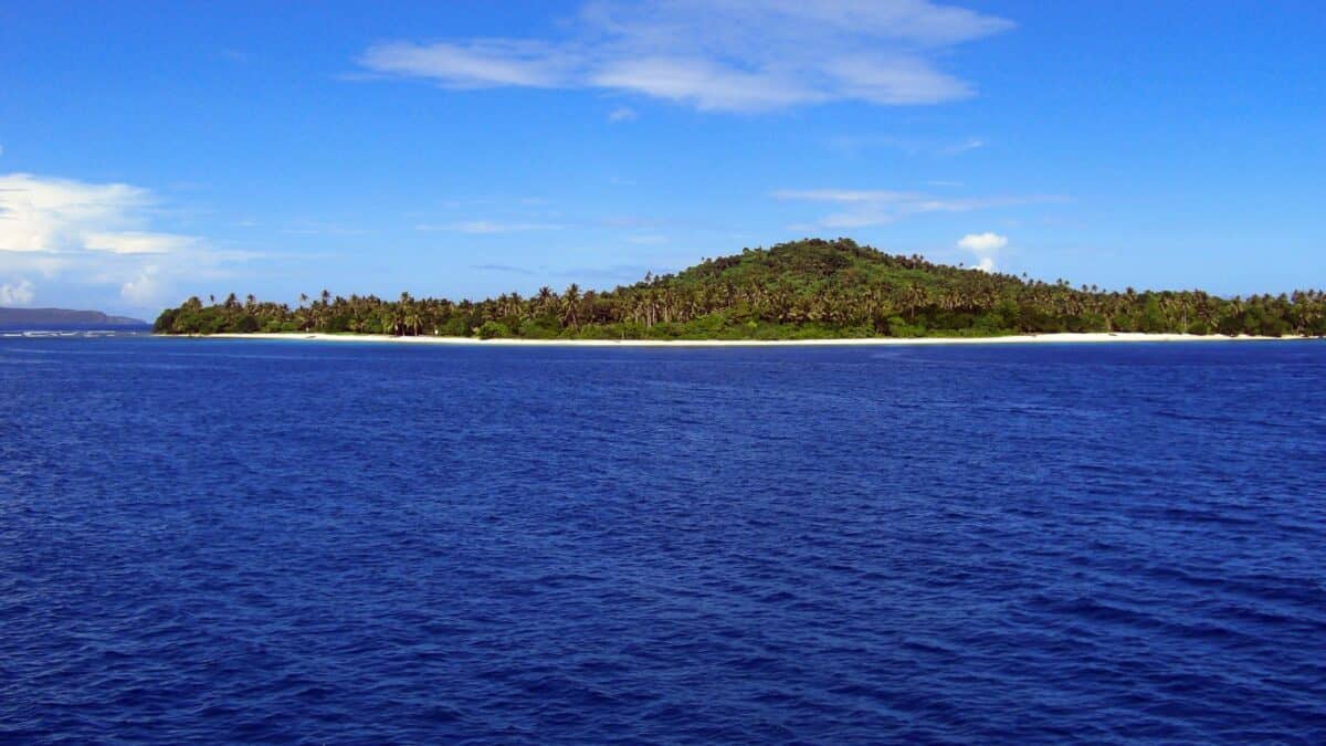 A panoramic view of a secluded tropical island with white sandy beaches surrounded by the blue ocean.