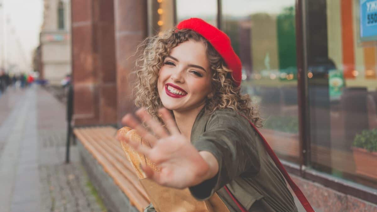 Woman wearing a red hat waving.
