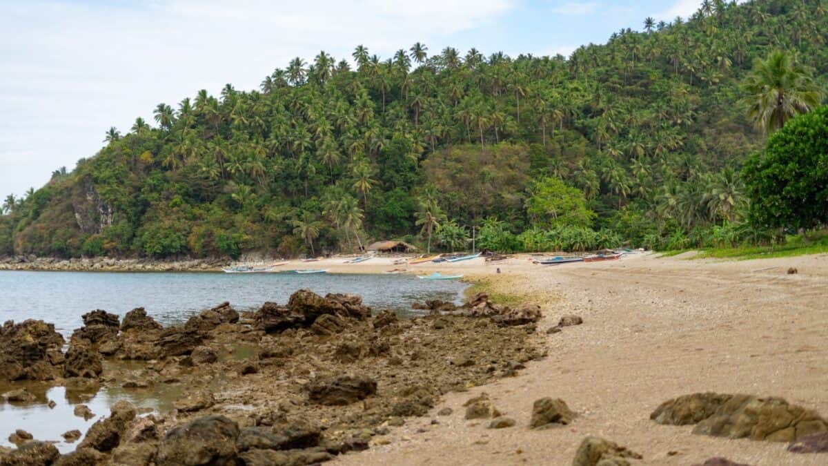 16 Survivor Locations that Would Actually Make Super Cool Vacation Destinations 15 White sand beach with rocky shore in Camarines Sur in the Philippines.