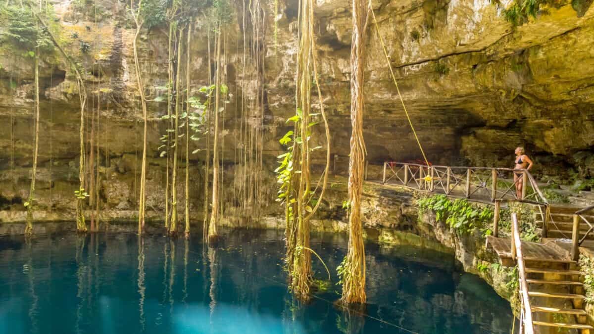 A woman standing by the bridge in Cenote Oxman.