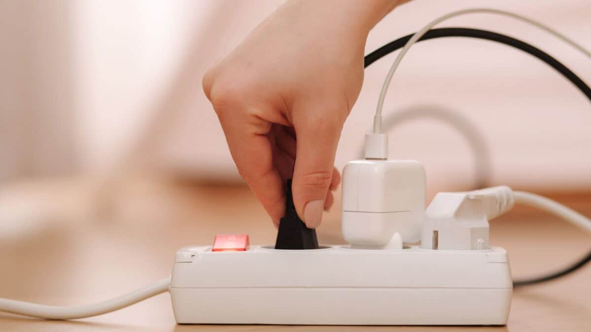20 Ultimate No-Nos of Cruise Packing—Learn What's Banned 12 A person's hand is plugging a black plug into a white power strip loaded with other adapters, on a wooden surface. the power strip has a red switch and is filled with plugged in devices.
