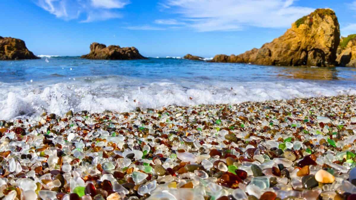 colorful glas on beach with waves lapping on shore