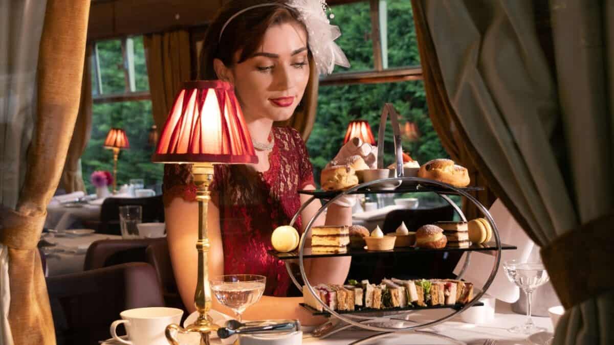 A woman in a vintage outfit enjoying an afternoon tea service on the luxurious Golden Eagle Danube Express train.