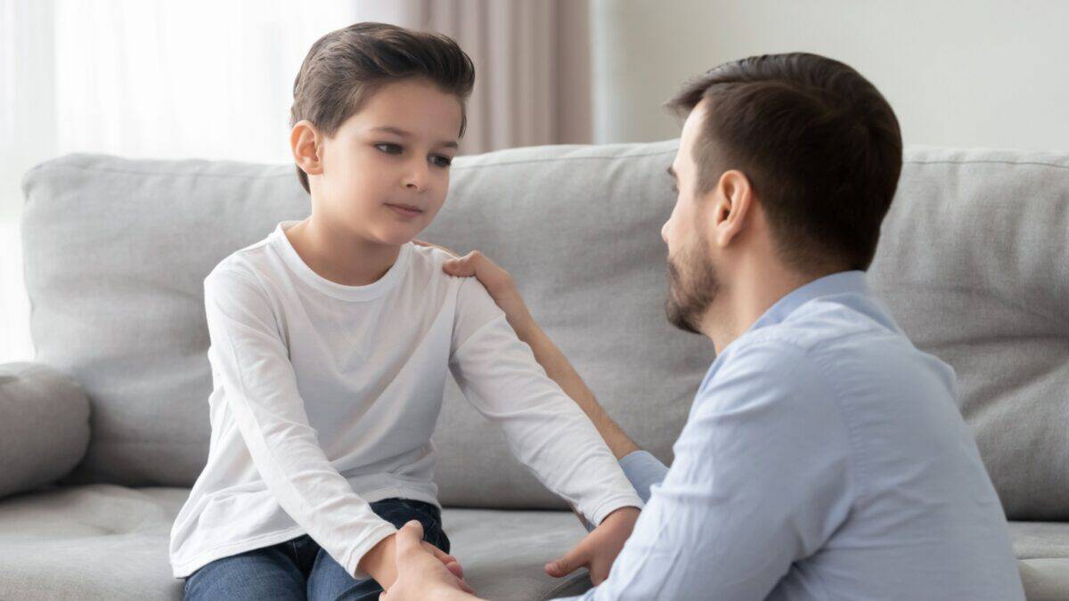 A little boy being apologetic as his dad talking to him.