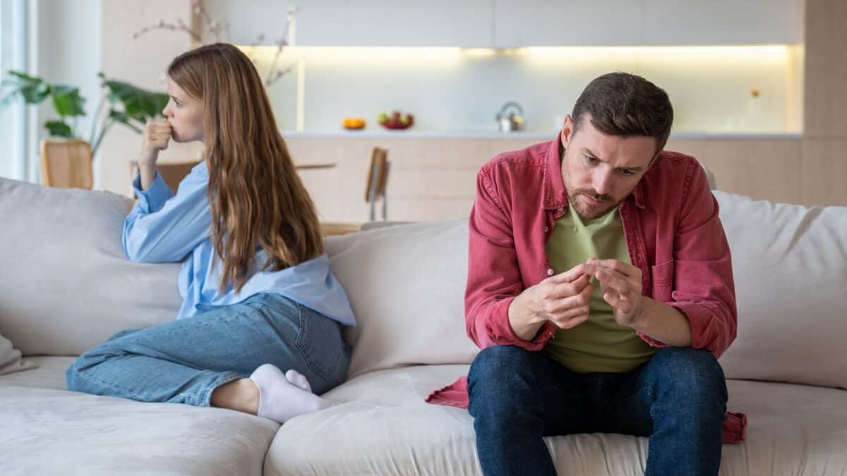 Inside the Narcissist's Playbook: 20 Tactics to Control and Confuse 22 A man and woman sitting on a couch, facing away from each other. the man is focused on his smartphone, while the woman looks away thoughtfully, suggesting tension or disagreement.