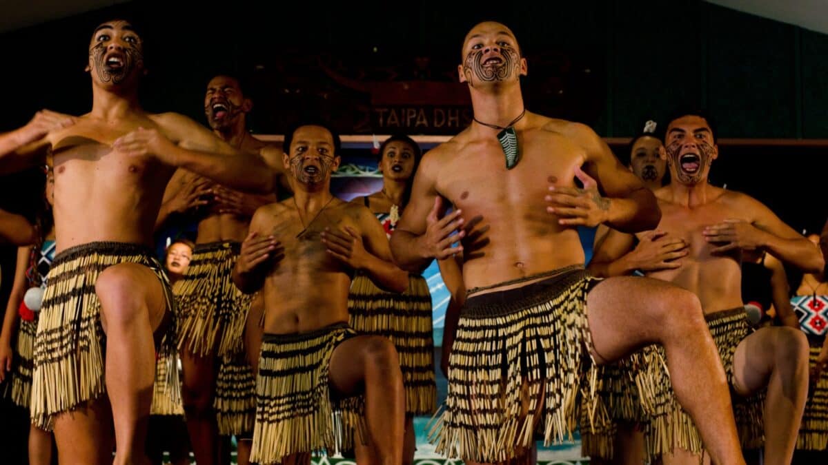 17 Friendliest Cities In The World 5 A group of māori men performing a traditional haka dance, wearing piupiu (flax skirts) and performing with expressive facial gestures and body movements.
