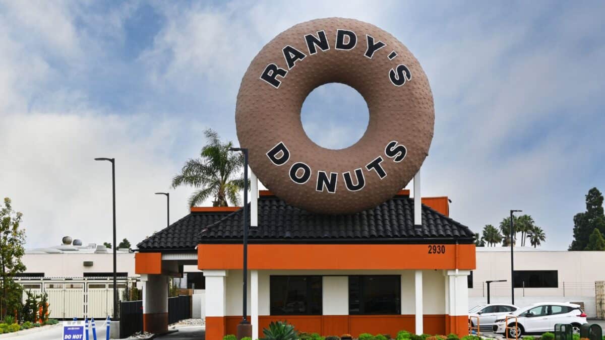 A view of randy's donuts shop featuring a large, iconic donut sculpture atop the building under a cloudy sky.